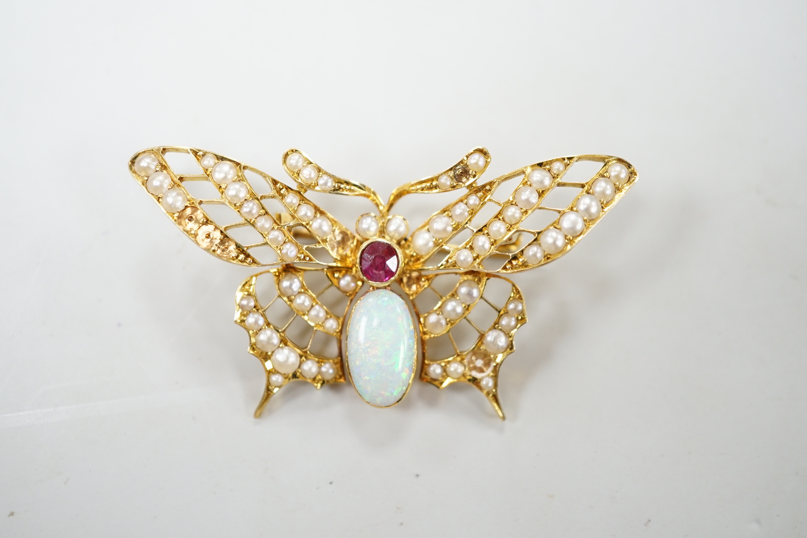 A yellow metal ruby, white opal and seed pearl cluster set bug brooch, width 48mm, gross weight 7 grams